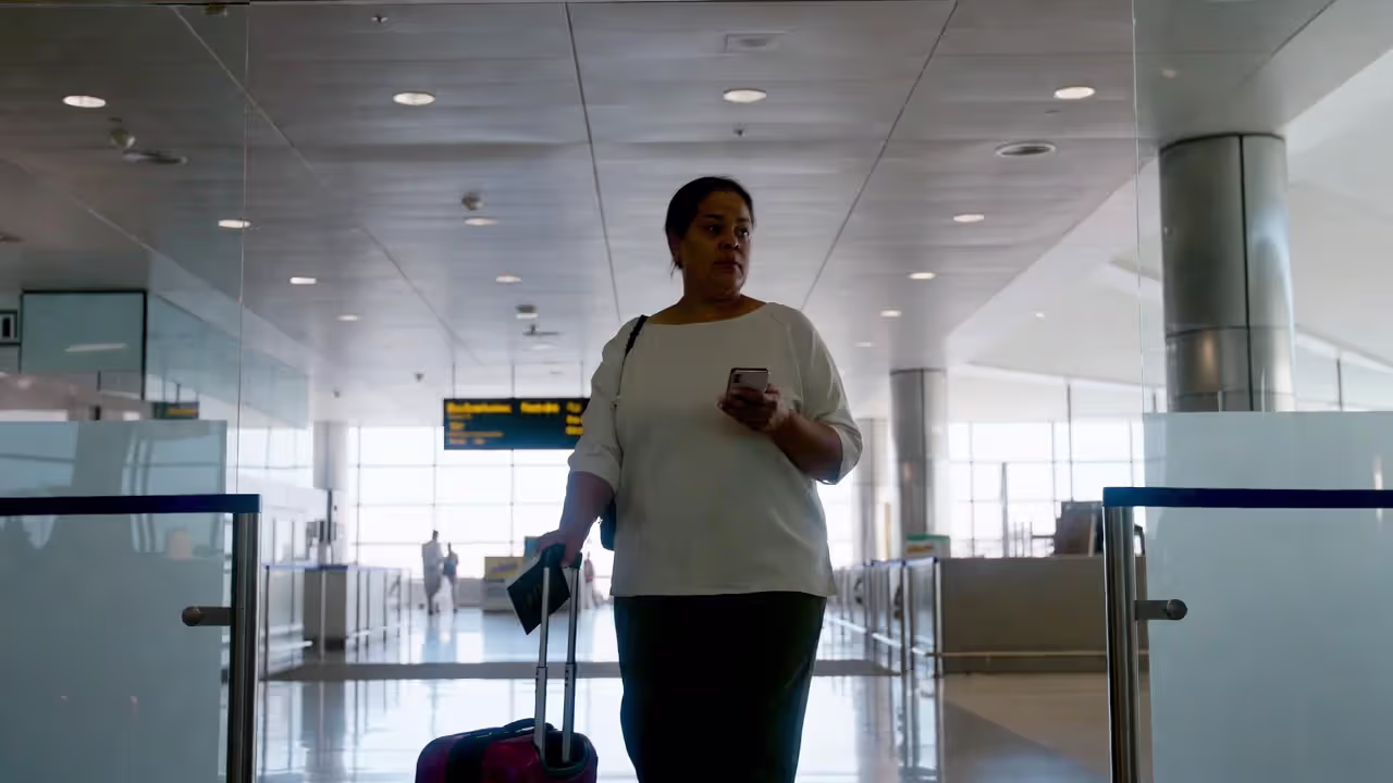 Solo female traveler at airport with passport and phone