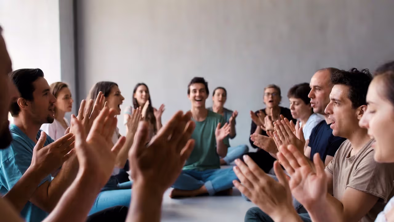 Group clapping and chanting during the warm-up phase of a laughter yoga session.