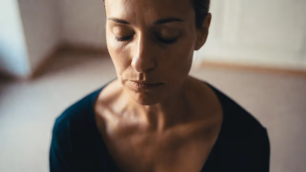 Person meditating with relaxed posture and attention on natural breathing