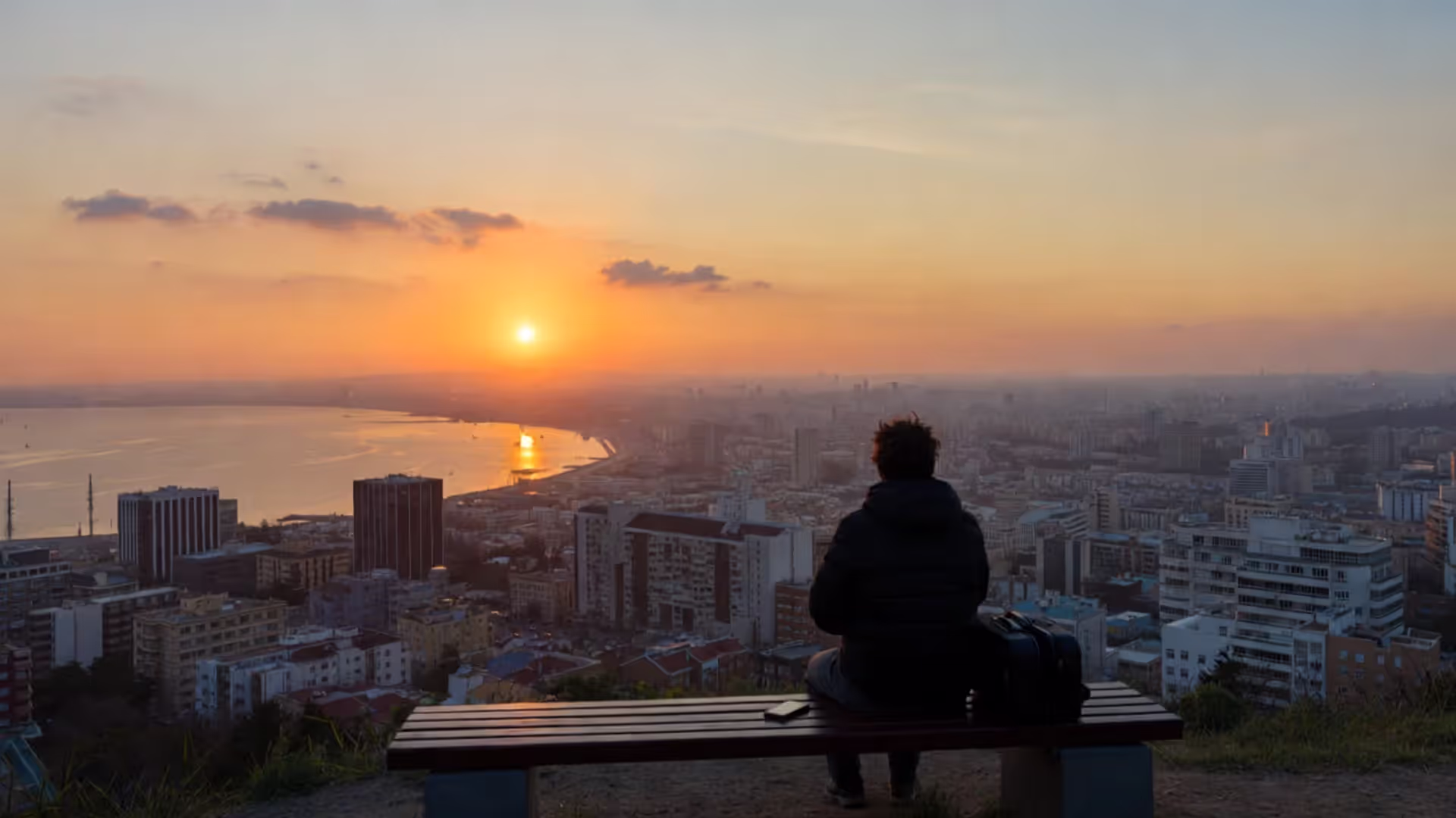 Traveler sitting quietly overlooking a coastal city with phone put away.